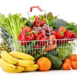 Wire shopping basket with groceries isolated on white background